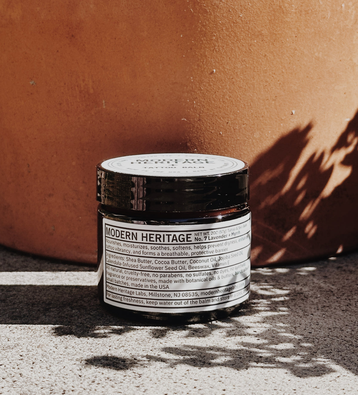 Modern Heritage tattoo balm jar against a terracotta pot