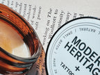 Modern Heritage tattoo balm jar and lid resting on an open book