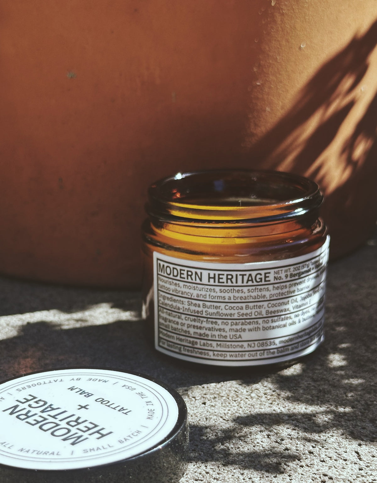 Modern Heritage tattoo balm jar against a terracotta pot