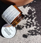 Modern Heritage tattoo balm jar tipped on concrete in dappled light